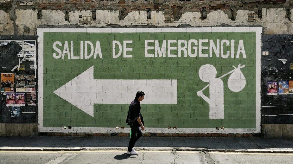 A man walks by an emergency exit graffiti mural on a street in Málaga, Spain.